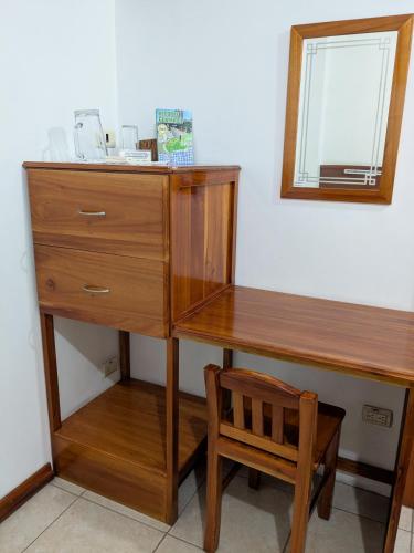 a wooden desk with a mirror and a wooden chair at Hostal Macaw in Guayaquil