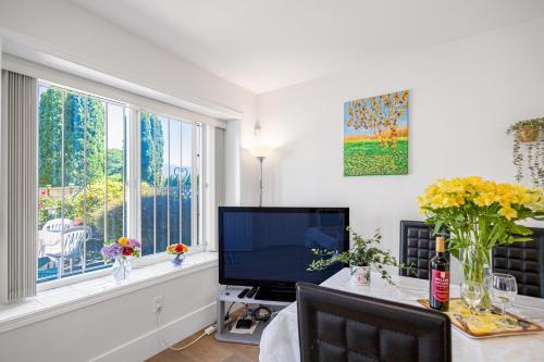 a living room with a television and a table with flowers at 2 Bds suite beautiful Yard near PNE in Vancouver