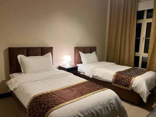 a bedroom with two beds and a lamp at شقه ليالي المارينا اطلاله بحريه عوائل in King Abdullah Economic City