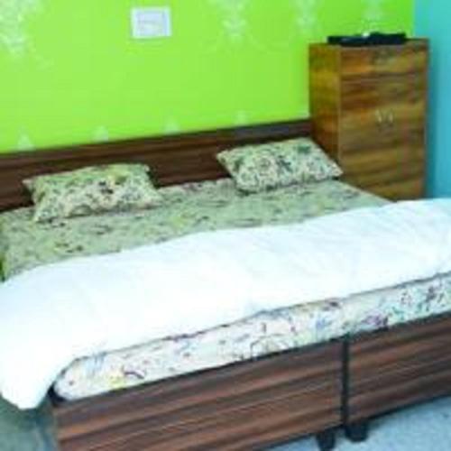 a bed in a room with a green wall at Phooldei Homestay By StayApart in Devaprayāg