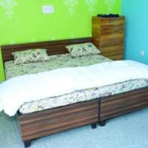a bed with a wooden frame in a bedroom at Phooldei Homestay By StayApart in Devaprayāg