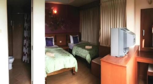 a hotel room with two beds and a television at Loei Orchid Hotel in Loei