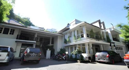 a white house with cars parked in front of it at Hotel Minahasa in Manado