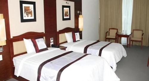 a hotel room with two beds and a table and chairs at BMC Ha Tinh hotel in Ha Tinh