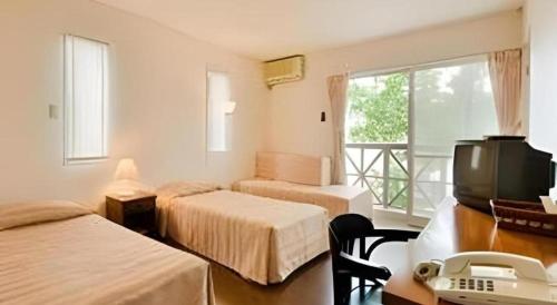 a room with two beds and a desk with a telephone at Country Inn The White Marine in Tonosho
