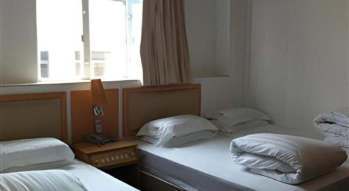 two twin beds in a room with a window at Man Va Hotel in Macau