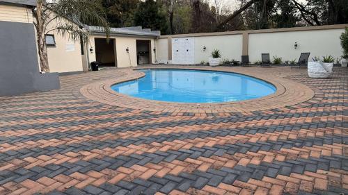 a brick walkway around a swimming pool in a yard at Los Angeles Lakefield guesthouse in Benoni