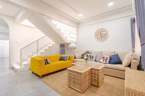 a living room with a yellow couch and a table at Kevin's House at Nimman - Premier Suite 2BR 2Bath, Tranquility in Nature in Chiang Mai