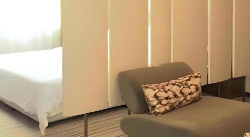 a room with a chair and a bed and a pillow at Shanshui Trends Hotel-Bantian Dong Branch in Shenzhen