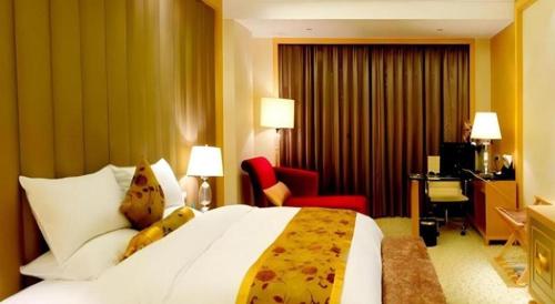 a hotel room with a large bed and a red chair at Jinjiang Grandlink Hotel in Quanzhou