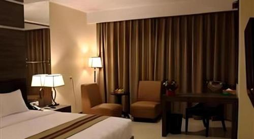 a hotel room with a bed and a desk at Mega Permata Hotel in Padangsidimpuan