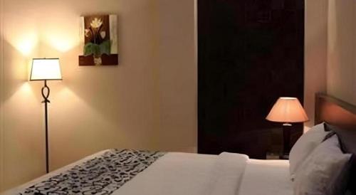 a bedroom with a white bed and a lamp at Mega Permata Hotel in Padangsidimpuan