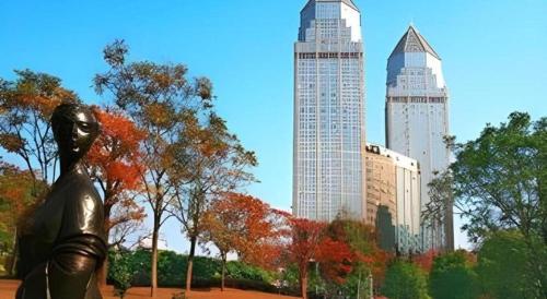 a statue of a woman in a park with buildings at Jinhua World Trade Hotel in Jinhua