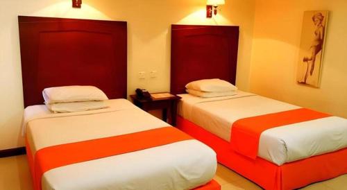 two beds in a room with red and white at Hotel Dynasty in Tarakan