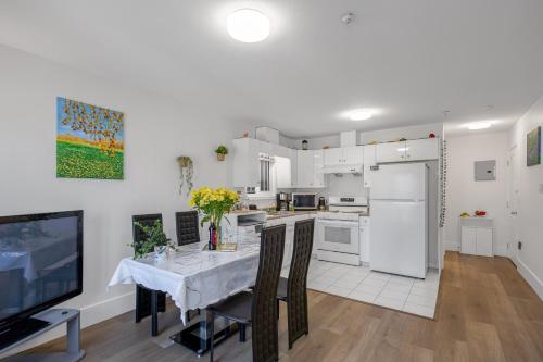 a white kitchen with a table and a television at 2 Bds suite beautiful Yard near PNE in Vancouver