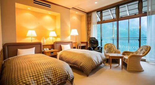 a bedroom with two beds and a large window at Hotel Hikyounoyu in Miyoshi