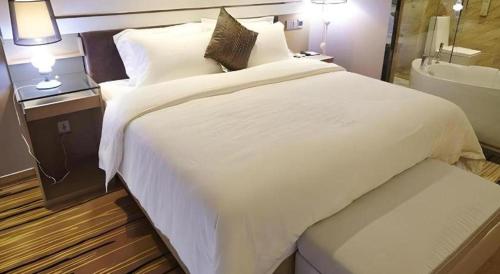 a bedroom with a large white bed and a bathroom at Lavande Hotel Xian Xiaozhai Subway Station Dayanta Branch in Xi'an