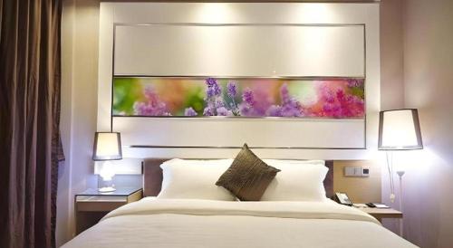 a bed in a hotel room with a painting above it at Lavande Hotel Xian Xiaozhai Subway Station Dayanta Branch in Xi'an