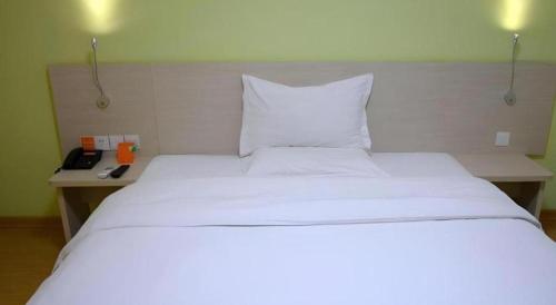 a bedroom with a white bed and a telephone at 7 Days Inn Jinan Changqing Jingshi West Road Center in Jinan