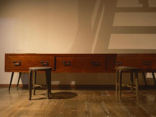 two bar stools in front of a wooden desk at 泊まれる文化交流施設 盆宿U bon-yadoU in Nishimonai