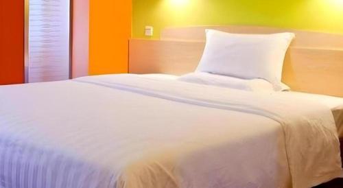 a large white bed in a bedroom with an orange wall at 7 Days Inn Luoyang Wangcheng Park Metro Station in Luoyang