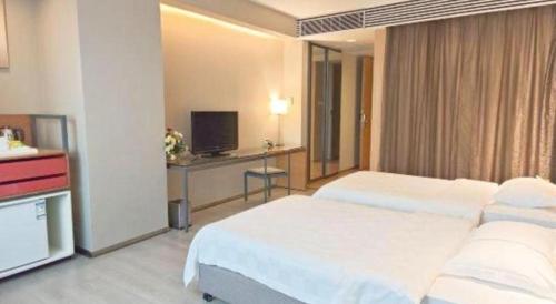 a hotel room with two beds and a television at Catic Hotel--Adjacent Buliding in Zhuhai