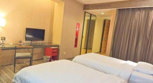 a hotel room with two beds and a desk with a television at Catic Hotel--Adjacent Buliding in Zhuhai
