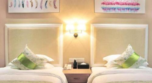 a bedroom with two beds with white sheets and green pillows at Catic Hotel--Adjacent Buliding in Zhuhai