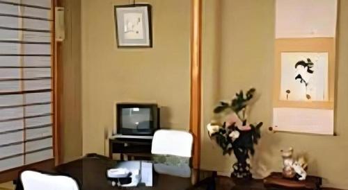 a living room with a table and a television at Kakeyu Onsen Hotel Kameya in Ueda