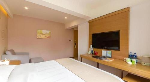 a bedroom with a bed and a desk and a tv at GreenTree Inn Xuancheng Jingxian Wannan First Street Express Hotel in Xuanzhou