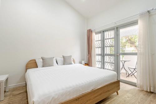 a white bedroom with a bed and a large window at Kevin's House at Nimman - Premier Suite 2BR 2Bath, Tranquility in Nature in Chiang Mai