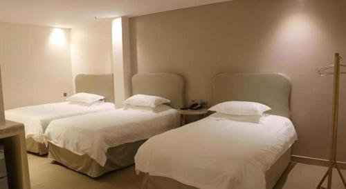 two beds in a room with white sheets and pillows at Leisurely Hotel Shenzhen in Shenzhen