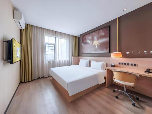 a hotel room with a large bed and a desk at IU Hotel Kunming Jinma Bijifang Joy City in Kunming