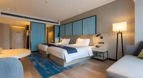 a hotel room with a bed and a desk and a couch at Echarm Hotel Aegean Shopping Park Zhonghuan Plaza in Tangshan