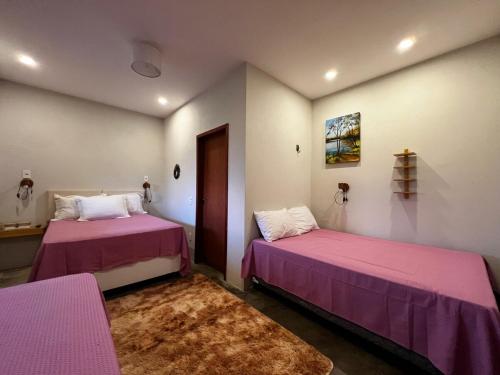 two beds in a room with pink sheets and a rug at Casa Lajeiro in Serra de São Bento