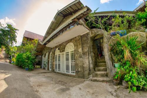 an old stone house with white doors and plants at Bee Hive Villa Kandy in Kandy