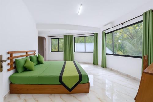 a bedroom with a green bed and windows at Bee Hive Villa Kandy in Kandy