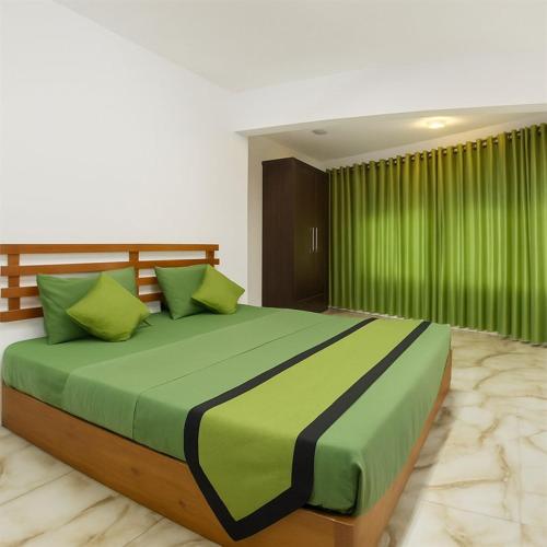 a bedroom with a large bed with green sheets at Bee Hive Villa Kandy in Kandy