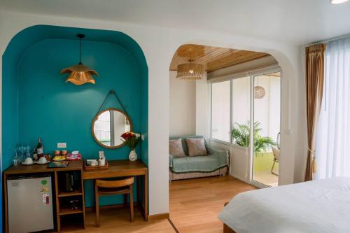 a bedroom with a blue wall and a desk with a mirror at Nontawa Villa Doichang in Ban Huai Khai