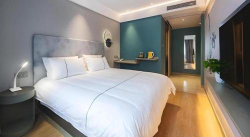 a bedroom with a large white bed and a blue wall at Magnotel Hotel Wuhan Jiangtan Lihuangpo Road Pedestrian Street in Wuhan