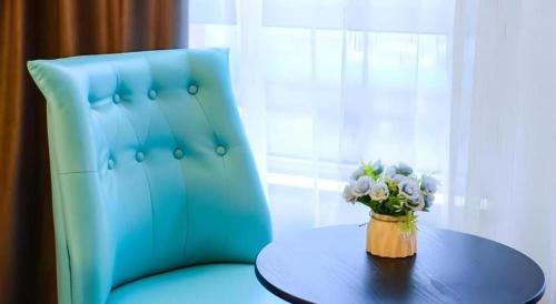 a blue chair with a vase of flowers on a table at Xana Hotelle Jinan Wuanfu Interchange Huafu International Square in Jinan