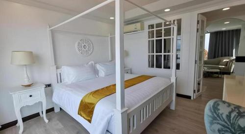 a white bedroom with a canopy bed and a chair at AT Kung Kra baen Hotel and Residence in Chanthaburi