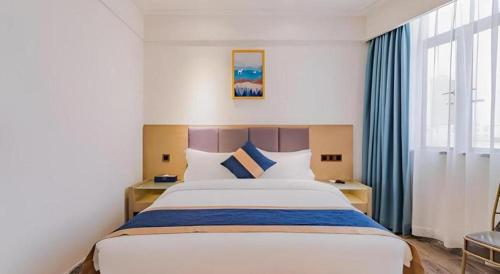 a bedroom with a large bed with blue and white pillows at Borrman Hotel Huizhou West Lake Shuidong Street in Huizhou