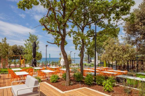 a patio with tables and chairs and a tree at Camping Homes Mon Perin in Bale