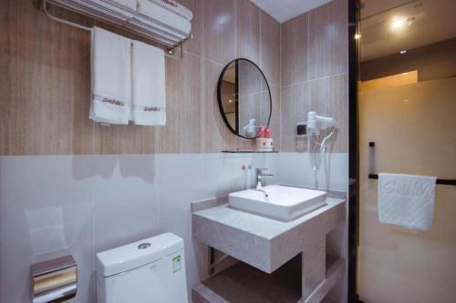 une salle de bain avec un lavabo et un miroir et des toilettes dans l'établissement Thank Inn Hotel Guangxi Hechi Yizhou Sankeshu, à Qingyuan