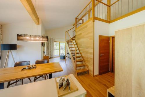 a living room with a wooden table and a spiral staircase at Landhaus Valfontana in Vandans