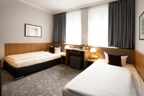 a hotel room with two beds and a desk at TOWNHOUSE Hotel in Frankfurt/Main