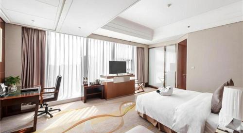 a bedroom with a bed and a desk and a television at Balan International Hotel in Dujiangyan