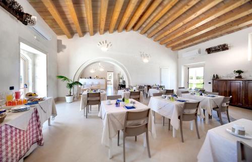 Un comedor con mesas y sillas blancas. en Addauro Resort, en Siracusa