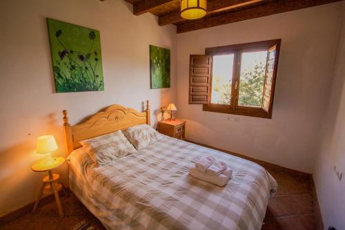 a bedroom with a bed with a wooden headboard and a window at Apartamento El Mirador Rocabella in El Chorro